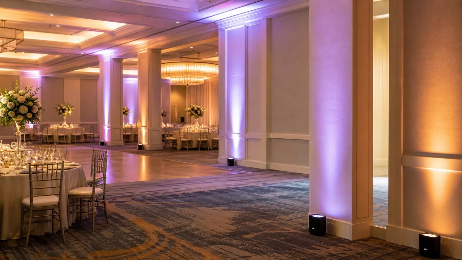 Battery powered uplights creating cable-free event lighting in an elegant ballroom
