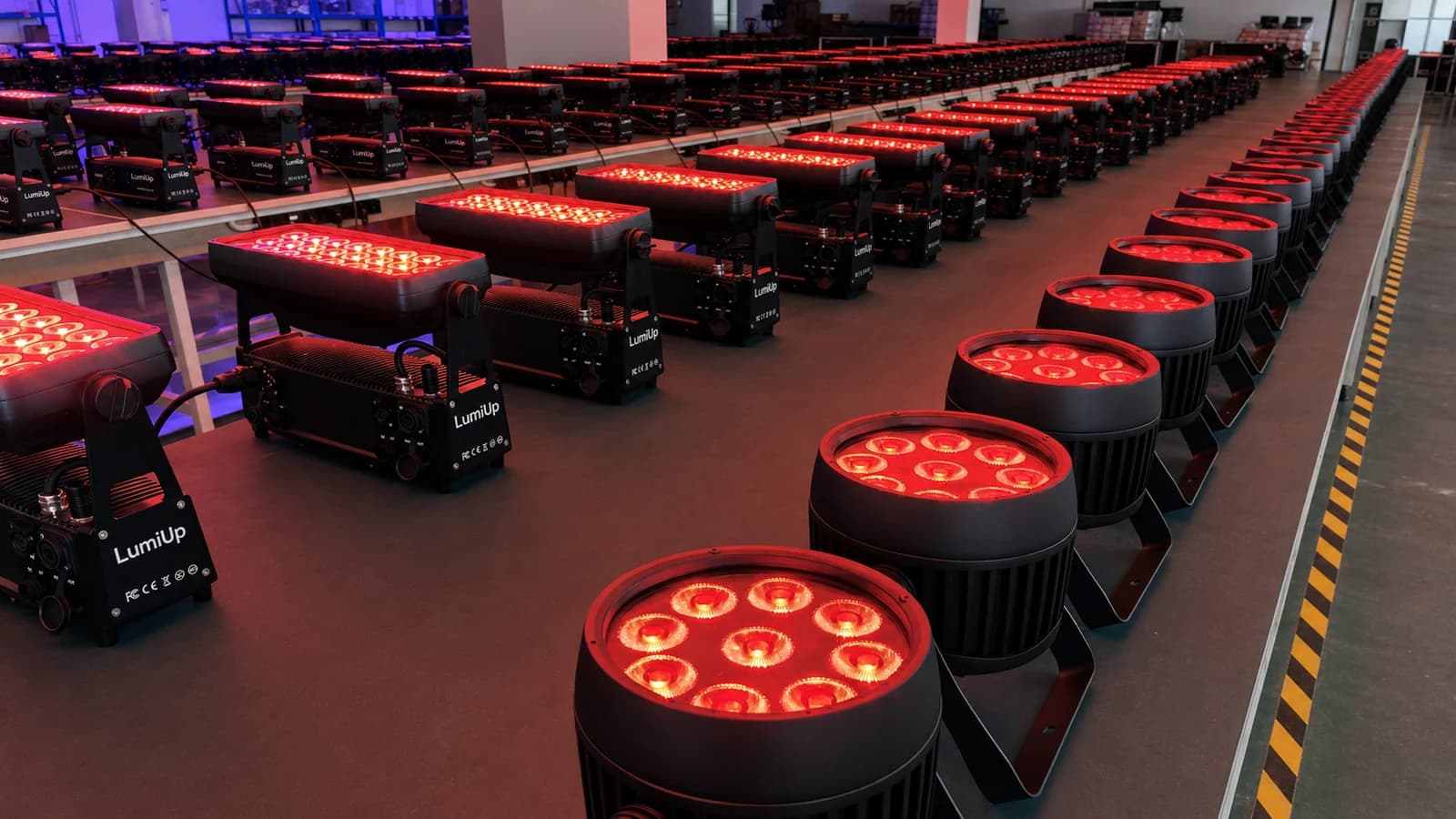 Rows of illuminated LumiUp PAR and wall-wash fixtures arranged for a batch check